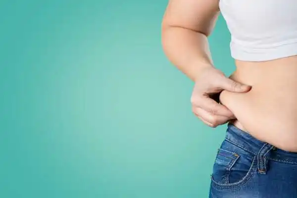 Image of woman pinching her love handles to show weight gain Wisbech